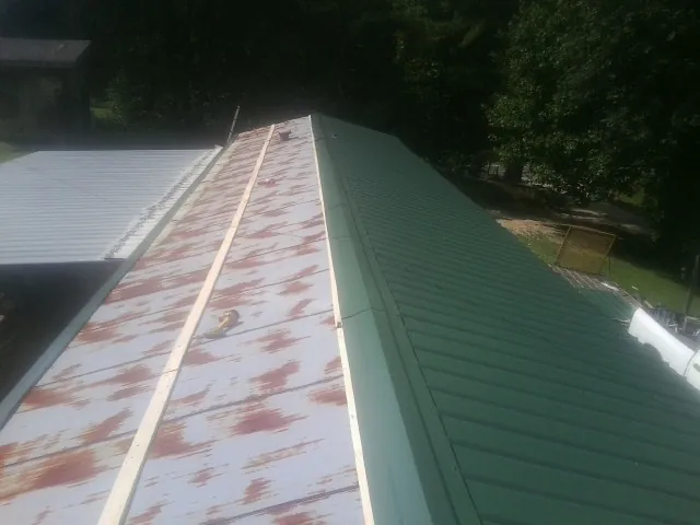 Old rusted panels beside newly installed green metal roofing — Wind Damage Roof Repair by Roofing Brothers in Cavour