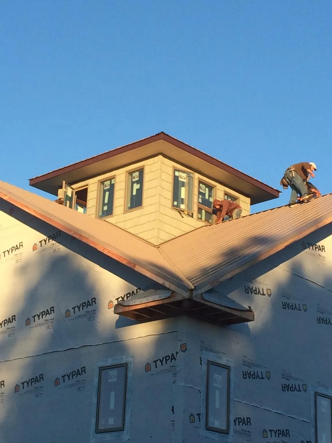Roofers working around a rooftop cupola on a new metal roof at sunset — Roof Waterproofing in Cavour by Roofing Brothers